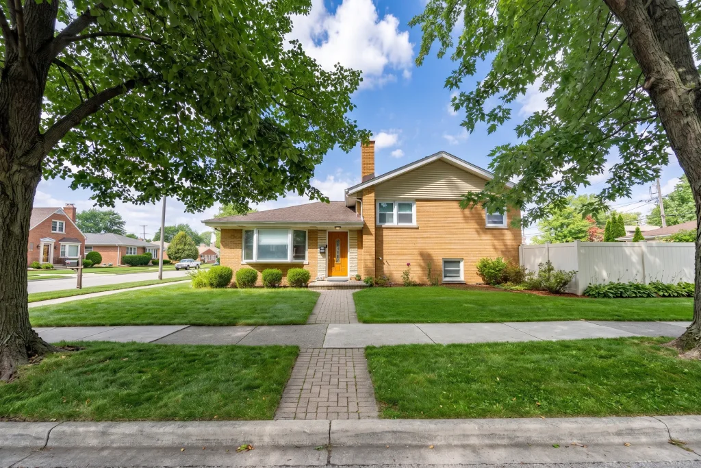 Mid Century Yellow Brick House Framed by Large Trees and Green Grass.jpg